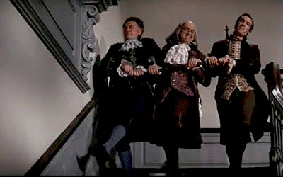 Robert Livingston, Benjamin Franklin, and Roger Sherman dancing down a staircase in the 1972 musical film about the writing of the Declaration of Independence, '1776'.